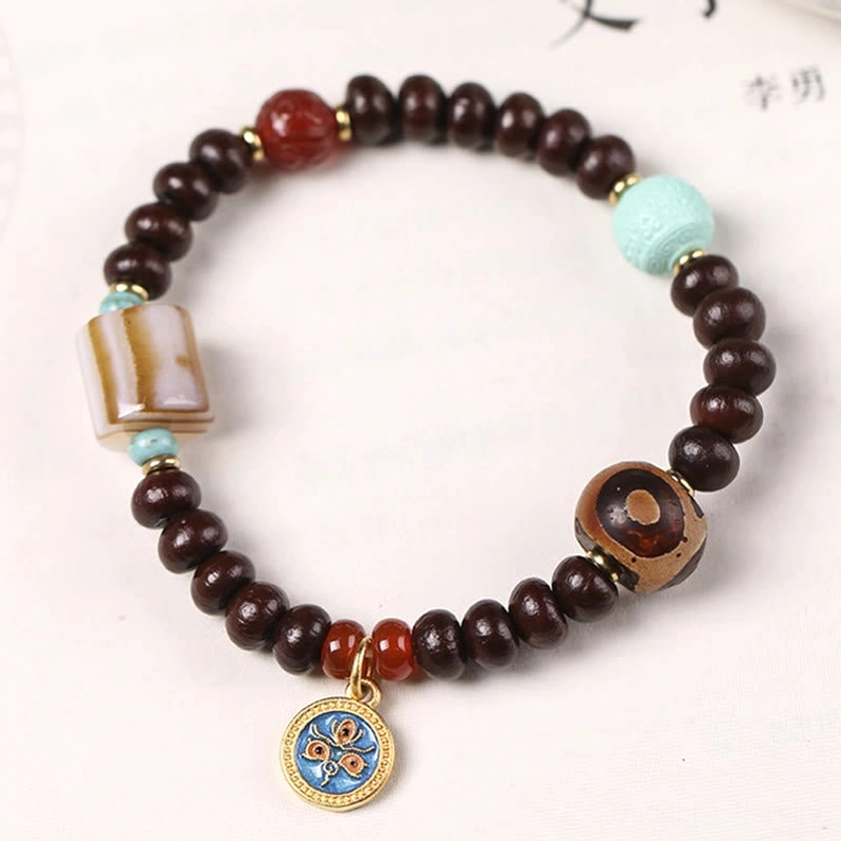 Handcrafted bodhi seed bracelet featuring striped agate and three-eye dzi bead on oriental paper background