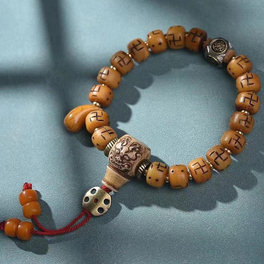 Tibetan Kirtimukha Buddhist bracelet with camel bone beads, guardian symbol charm, and protective woven tassel