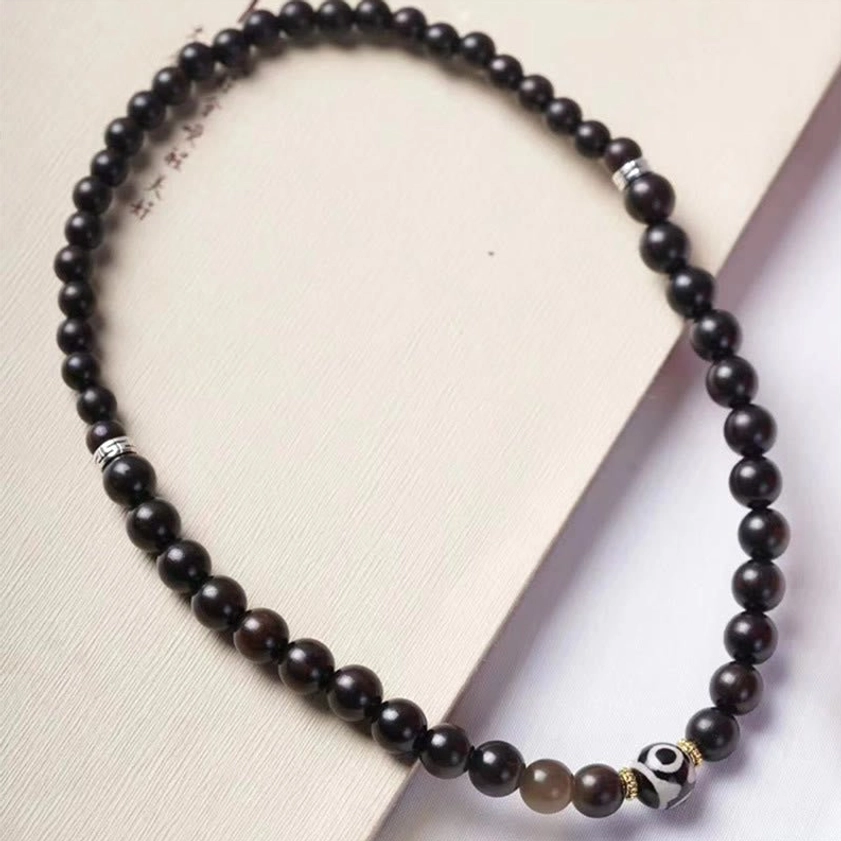 Tibetan prayer bead mala bracelet with mixed dark wooden beads light brown accent bead metal spacers and dzi charm top-down flat lay