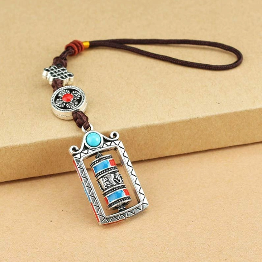 Tibetan prayer wheel keychain flat lay showing turquoise bead and geometric silver frame detail