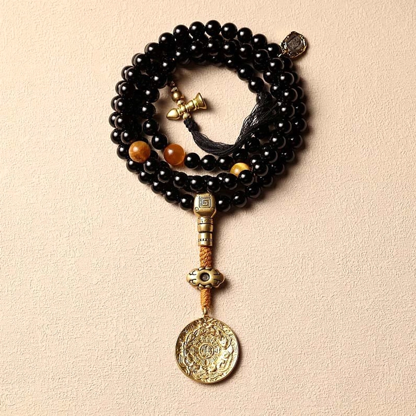 Tiger eye stone and bagua medallion charm mala beads on wooden surface