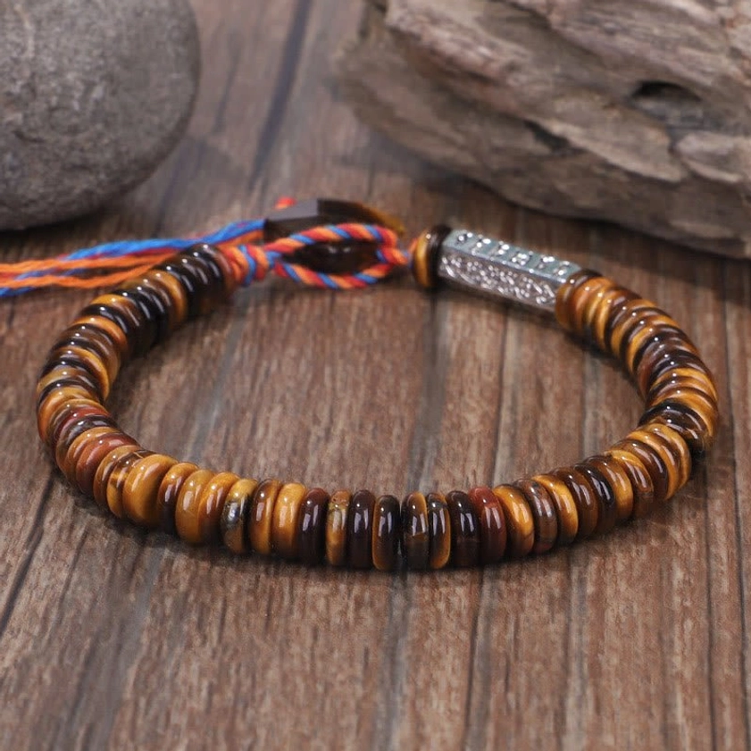 Natural tiger eye disc bead Buddhist bracelet with metal clasp and woven tassel on wooden surface