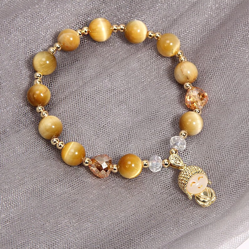 Handmade tiger eye Buddha bracelet with gold-tone metal accessories laid flat overhead