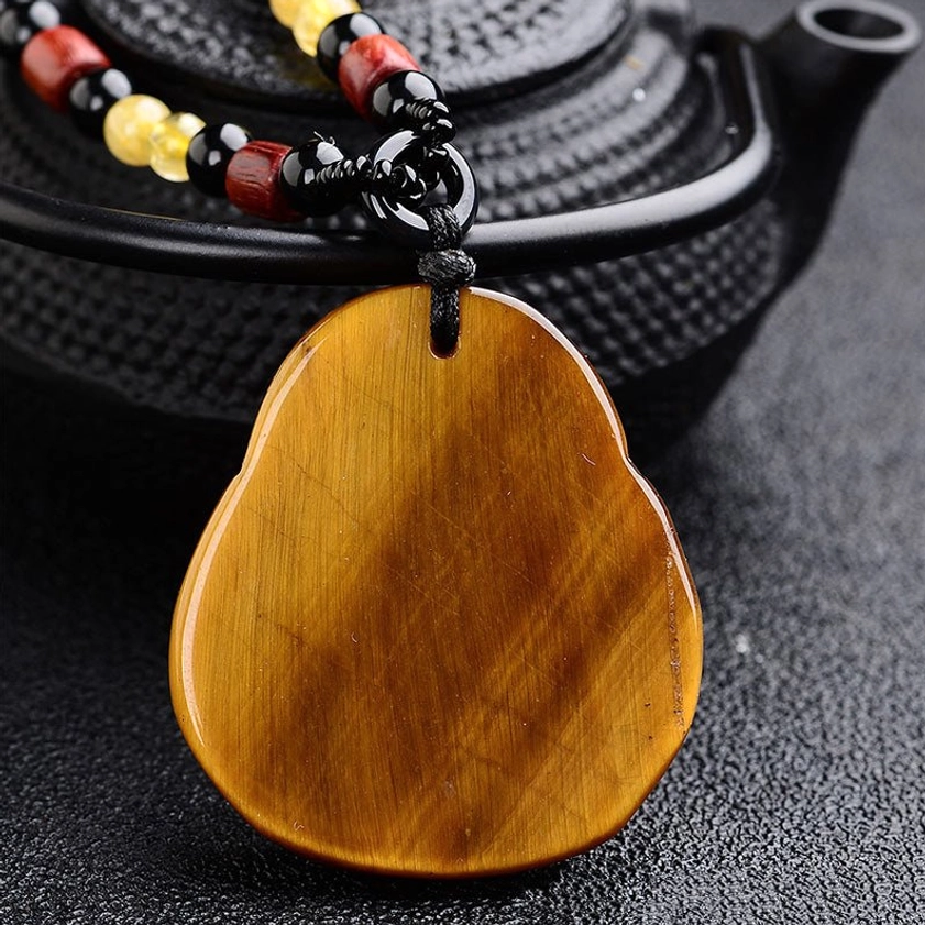 Back view of tiger's eye Buddha pendant showing smooth stone surface and natural stone grain