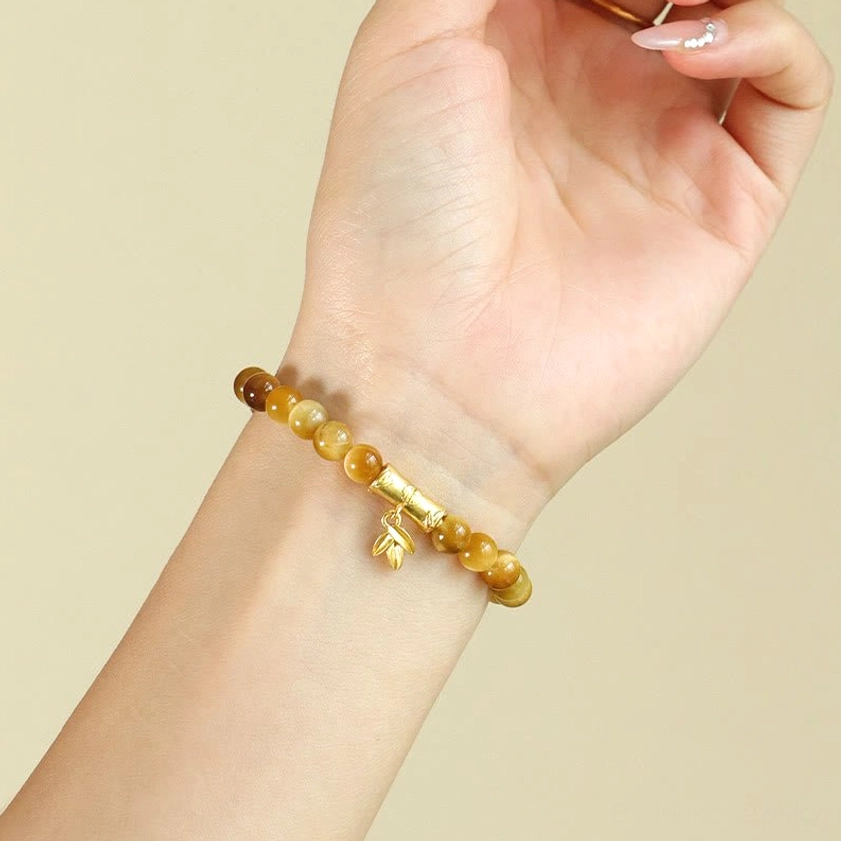 Side view of tiger eye stone buddhist bracelet with gold accent beads on wrist