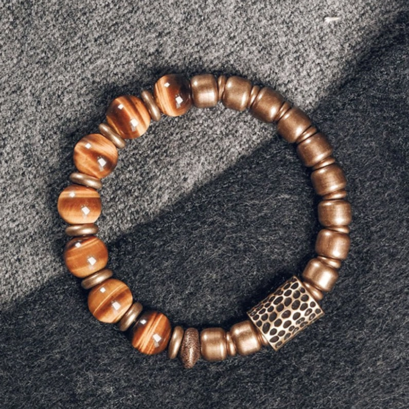 Tiger eye stone bracelet with rectangular hammered copper accent on grey woolen fabric, flat lay detail shot