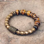 Tiger eye stone copper beaded bracelet with hammered brass spacers, overhead flat lay on textured stone background