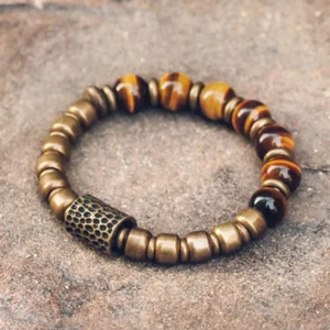 Tiger eye stone copper beaded bracelet with hammered brass spacers, overhead flat lay on textured stone background