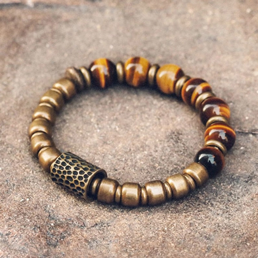 Tiger eye stone copper beaded bracelet with hammered brass spacers, overhead flat lay on textured stone background