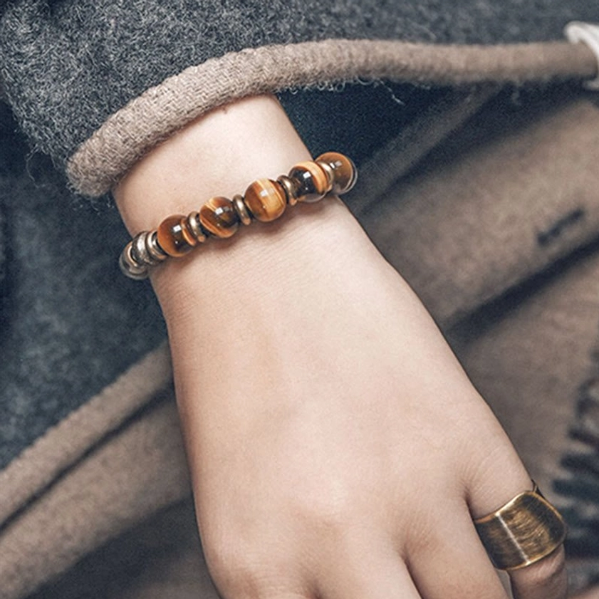 Simplified bead design tiger eye stone bracelet worn with matching ring on beige woolen coat, side wrist view