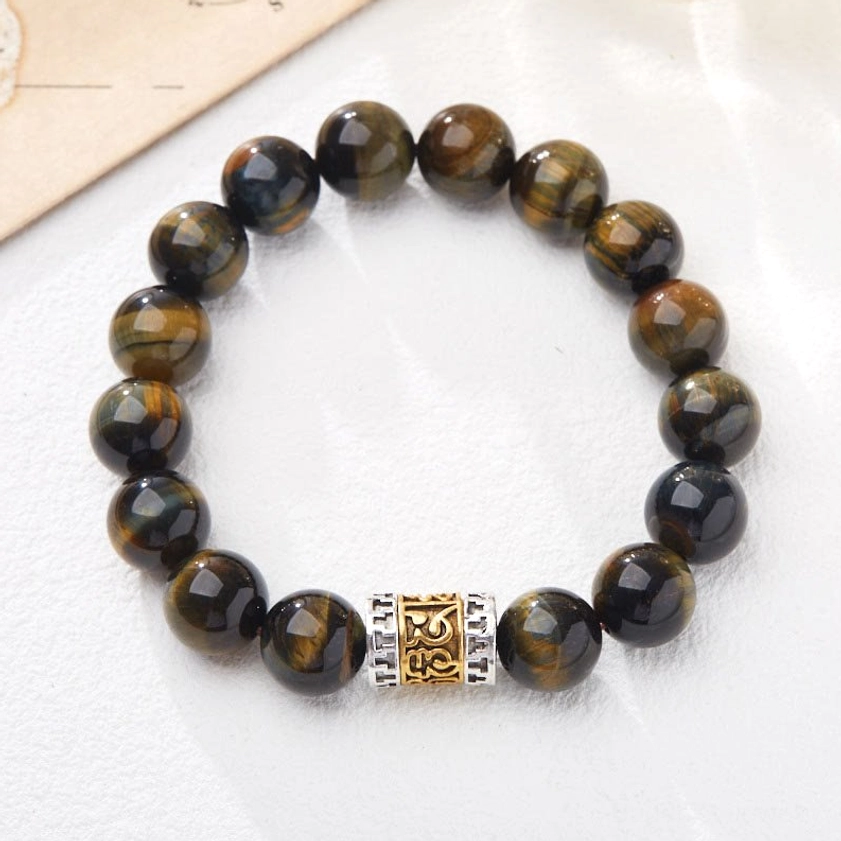 Buddhist courage bracelet with natural tiger eye beads and engraved mantra charm on light neutral background