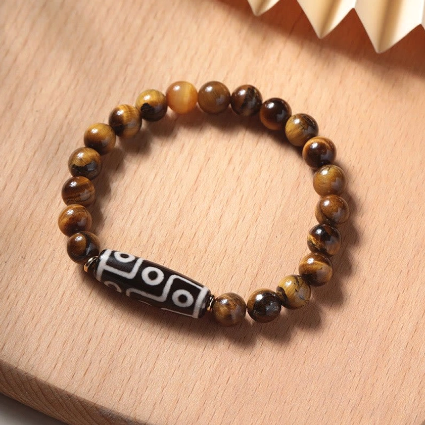 Tiger eye and nine-eye dzi bead protection bracelet with natural golden-brown striped beads on wooden display