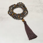 108 bead tiger eye hematite prayer mala necklace close-up overhead view with dark brown tassel