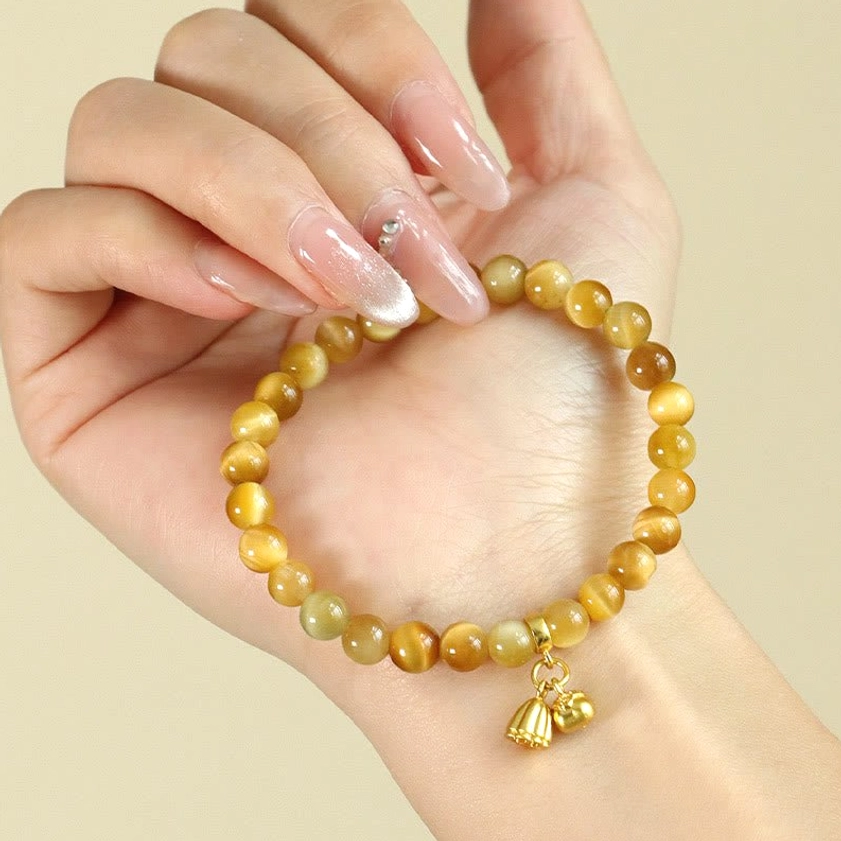 Close-up of hand holding tiger eye buddhist bracelet with gold lotus charm