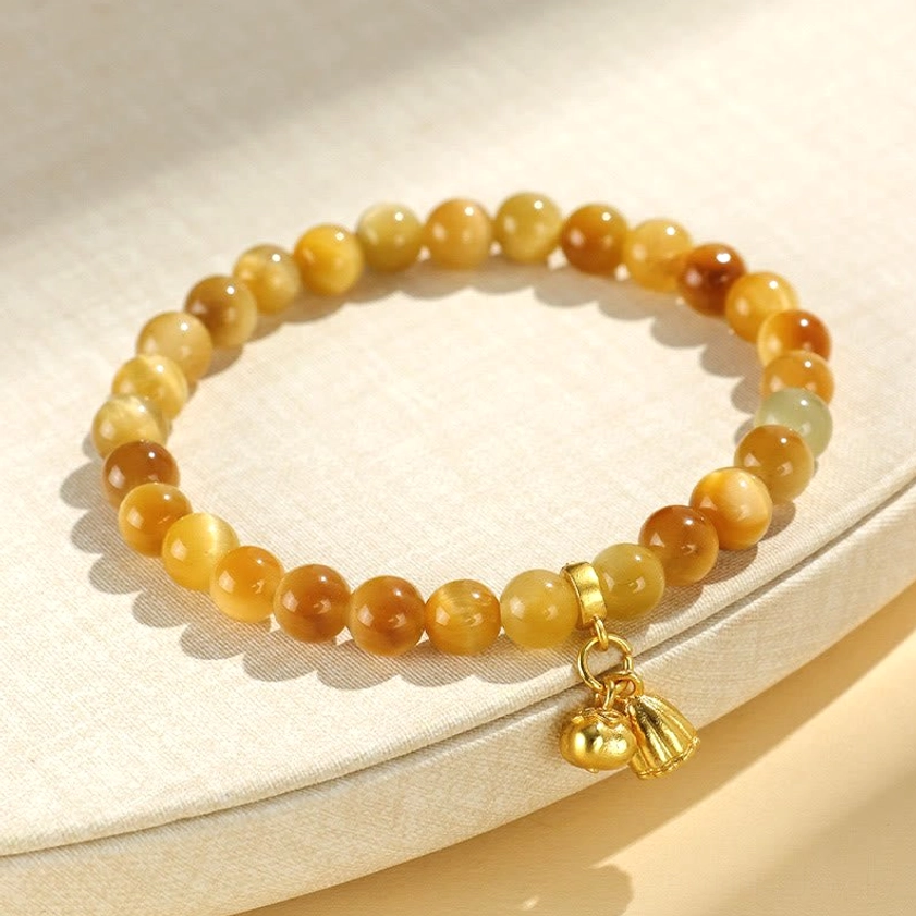 Tiger eye stone bracelet with lotus pendant on light beige fabric side view