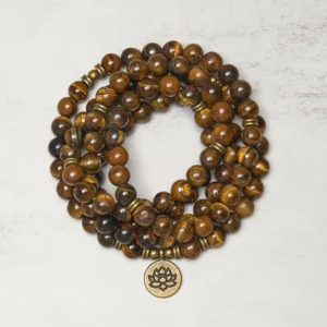 Tiger eye and lotus buddhist prayer mala beads flat lay top view with bronze lotus charm pendant and natural stone texture detail