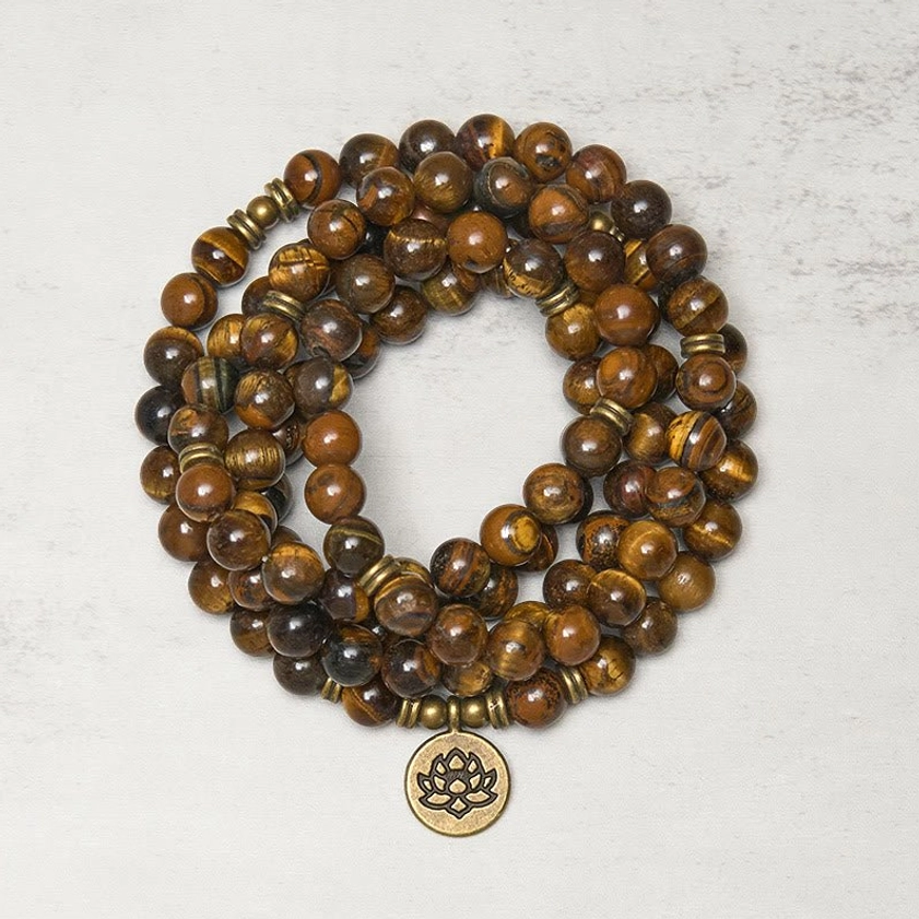 Tiger eye and lotus buddhist prayer mala beads flat lay top view with bronze lotus charm pendant and natural stone texture detail