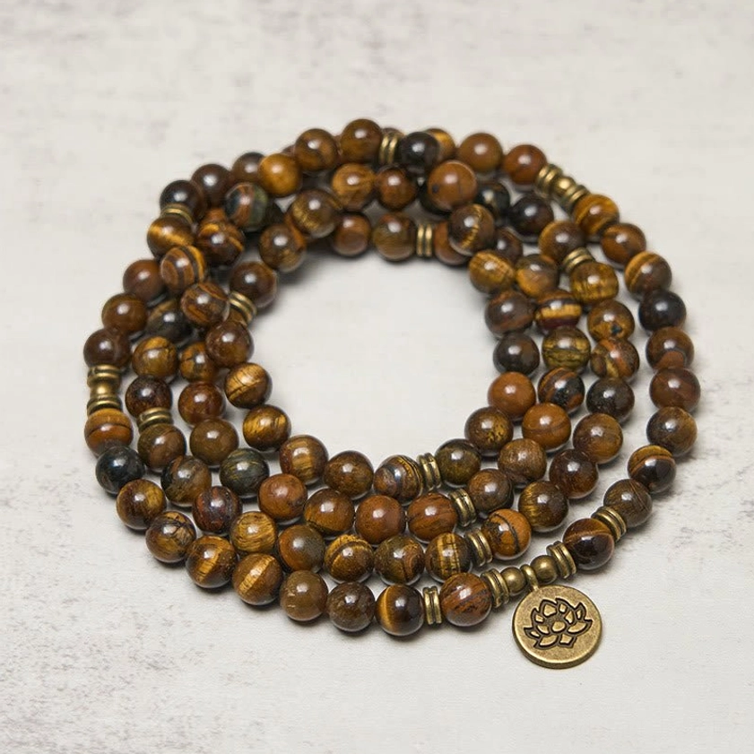 108 bead tiger eye mala bracelet with bronze spacer rings and lotus symbol close-up overhead view showing stone grain pattern