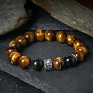 Tiger Eye and Black Obsidian Buddhist protection bracelet with silver Buddha charm displayed on dark stone background