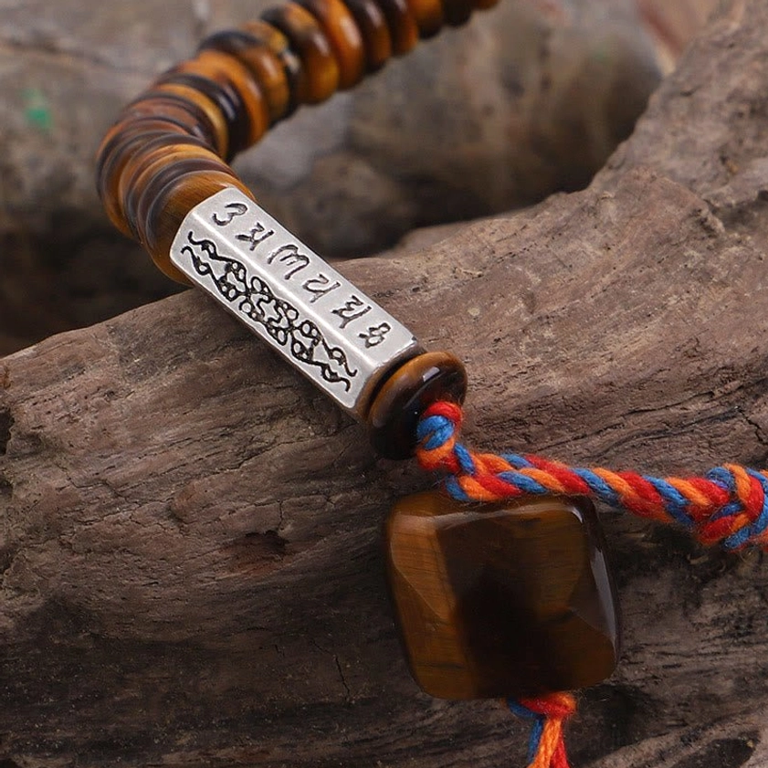 Close-up of tiger eye charm pendant with engraved silver om mantra tag and braided multicolor tassel