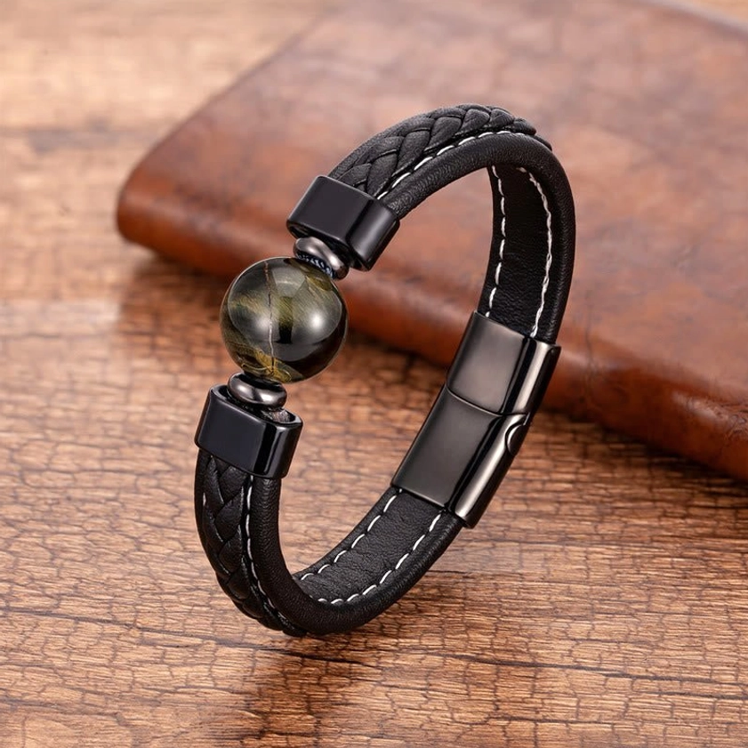 Tiger Eye Om Mani Padme Hum leather bracelet with golden-brown iridescent stone bead on wooden coaster, overhead view