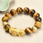 Tiger Eye Pixiu bracelet with Fu character and Om Mani Padme Hum charm, flat lay view