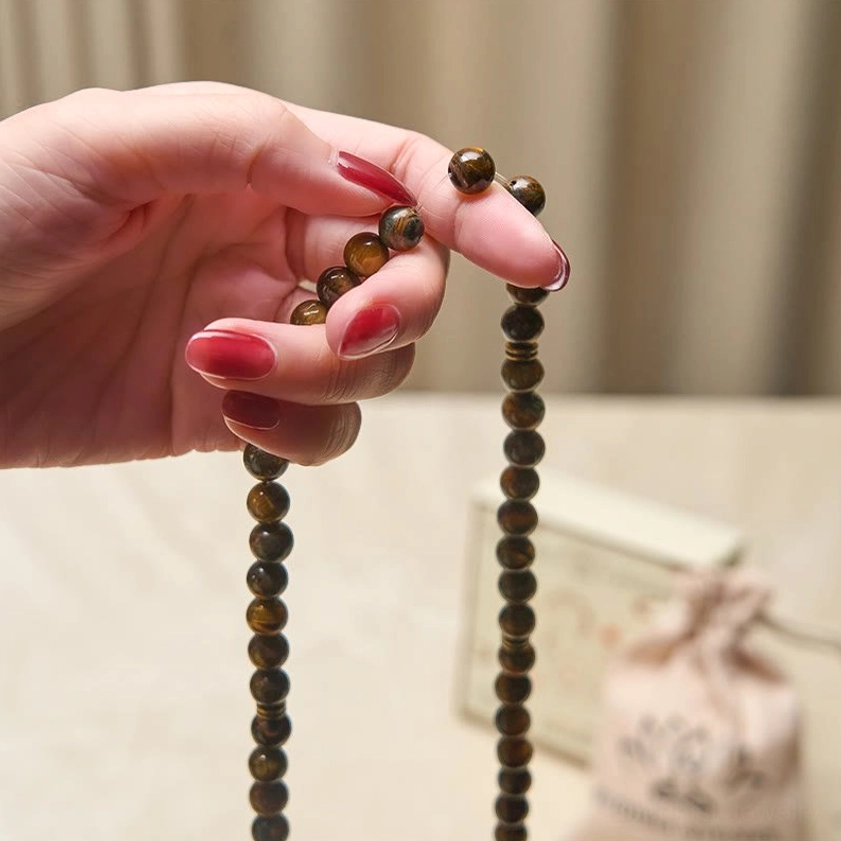 Tiger eye stone prayer beads held in hands close-up view of smooth round bead texture and natural striped grain pattern