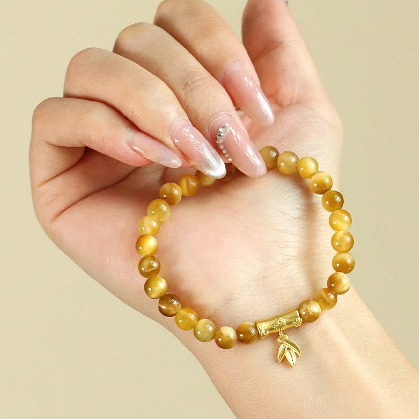 Woman wearing tiger eye buddhist bracelet with decorative gold charms on wrist