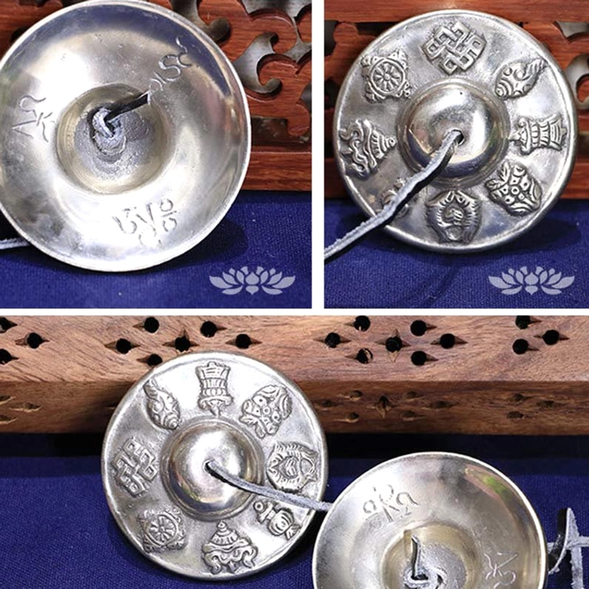 Buddhist tingsha bell showing inner mantra engraving, white copper metal, leather strap, side detail view