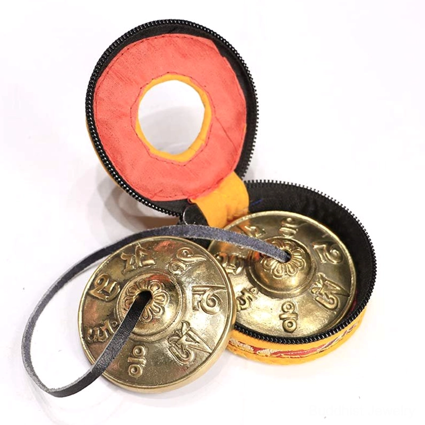 Tingsha cymbals with storage fabric pouches and leather strap on white background - six true words design