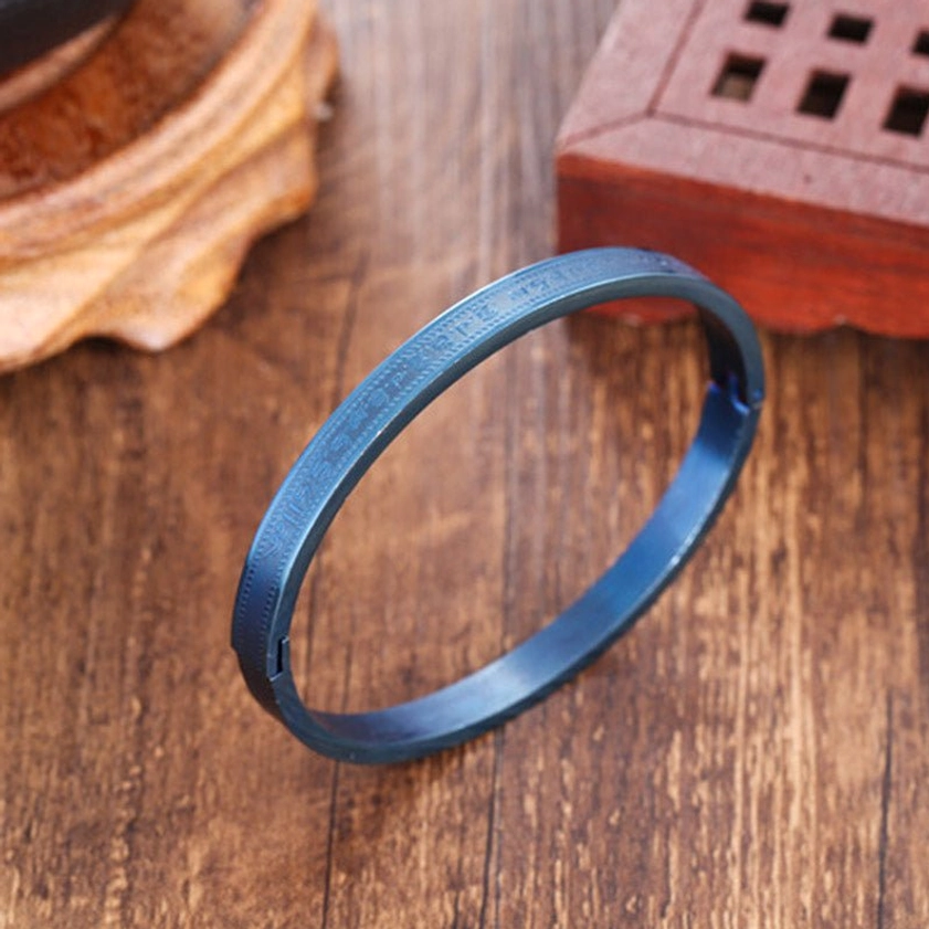 Matte burnt blue titanium steel blessing bracelet with smooth metal band surface, shown from oblique side angle