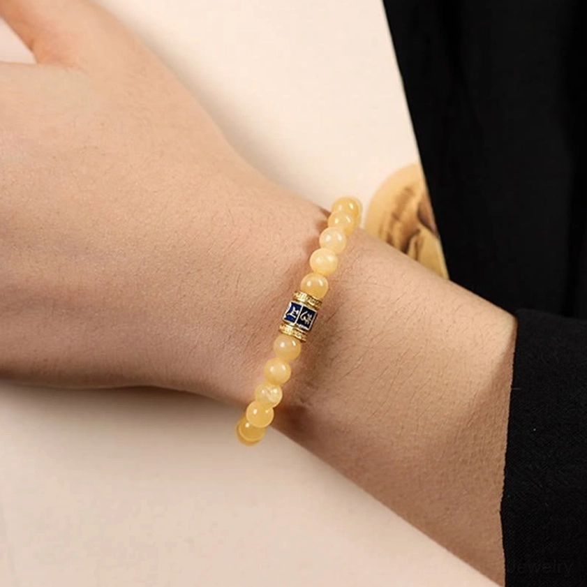 Topaz Buddhist bracelet worn on wrist close-up side view with engraved copper mantra charm clearly visible