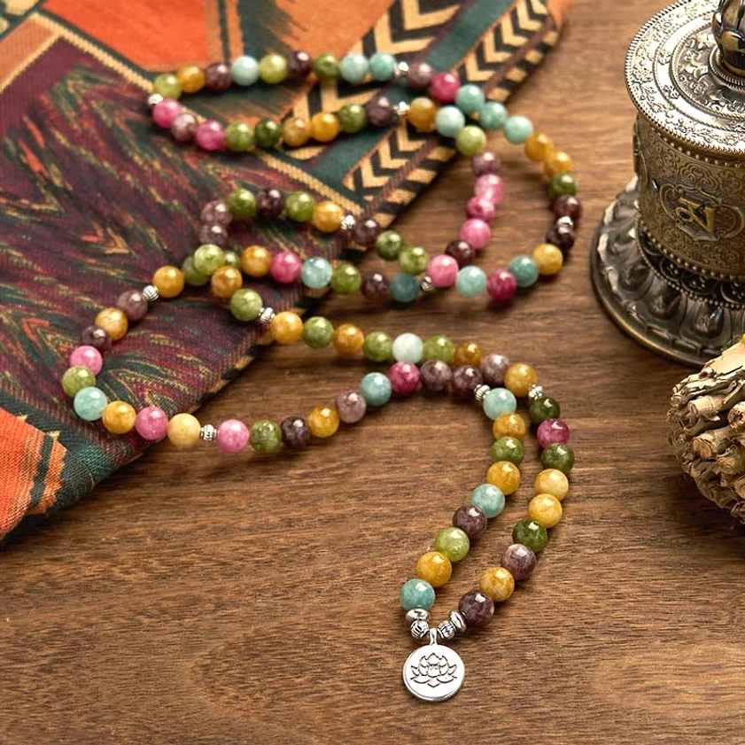 Handcrafted tourmaline 108 bead mala with lotus charm, mixed colored natural stones on wooden table