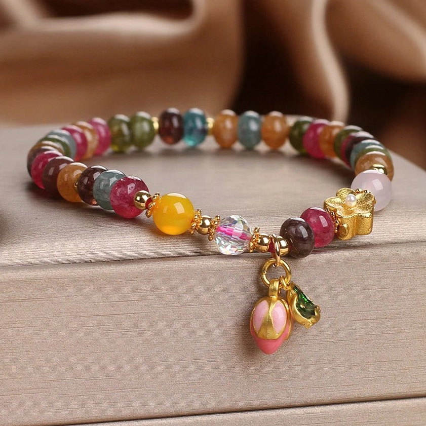 Tourmaline lotus seedpod wisdom bracelet front overhead view with multicolor beads and gold metal accents