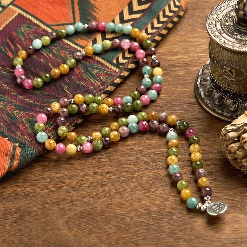 Beautifully draped tourmaline meditation mala with mixed colored beads and silver lotus charm on fabric