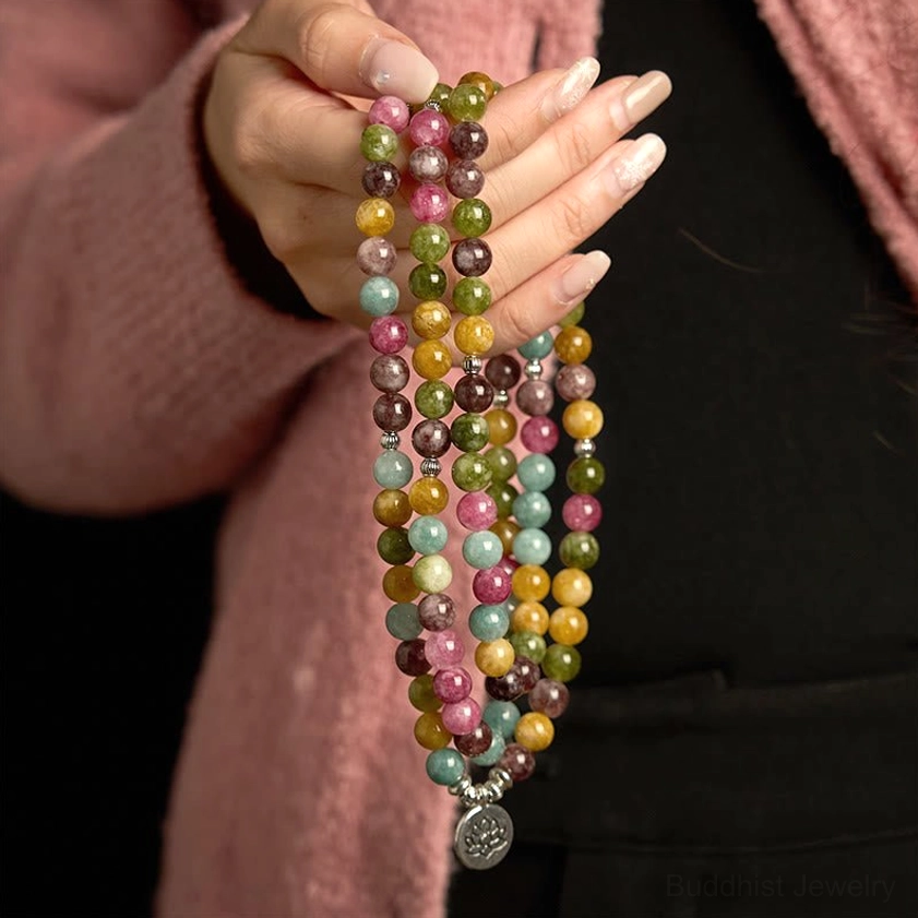 Close-up hand holding tourmaline Buddhist mala bracelet showing natural stone bead detail and quality