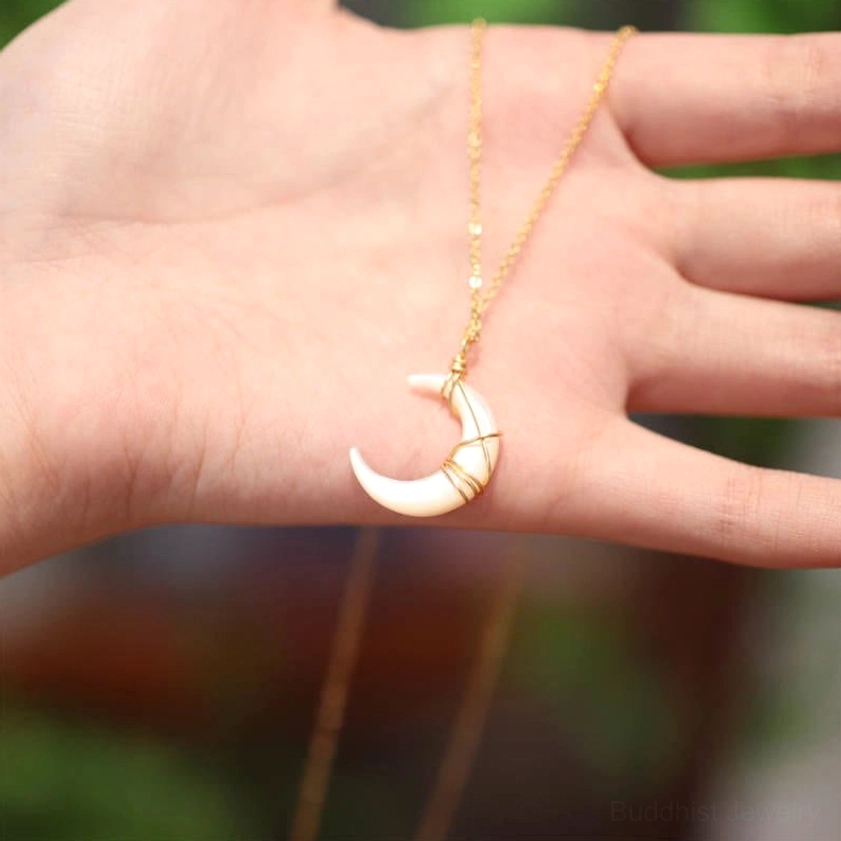 Natural Tridacna crescent pendant held in palm, top-down close-up showing iridescent stone finish and gold wire wrapping detail