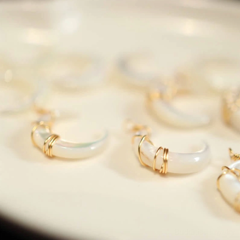 Unfinished natural Tridacna crescent moon shell blanks in hand, showing raw stone quality and iridescent white finish before wire wrapping