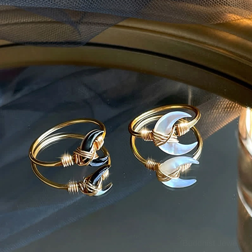 Black and white tridacna stone moon blessing rings side by side, flat lay comparison of both stone color options