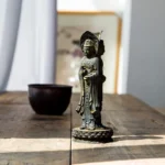 Triple-face Avalokitesvara resin statue left side view on wooden desk with rustic iron patina finish
