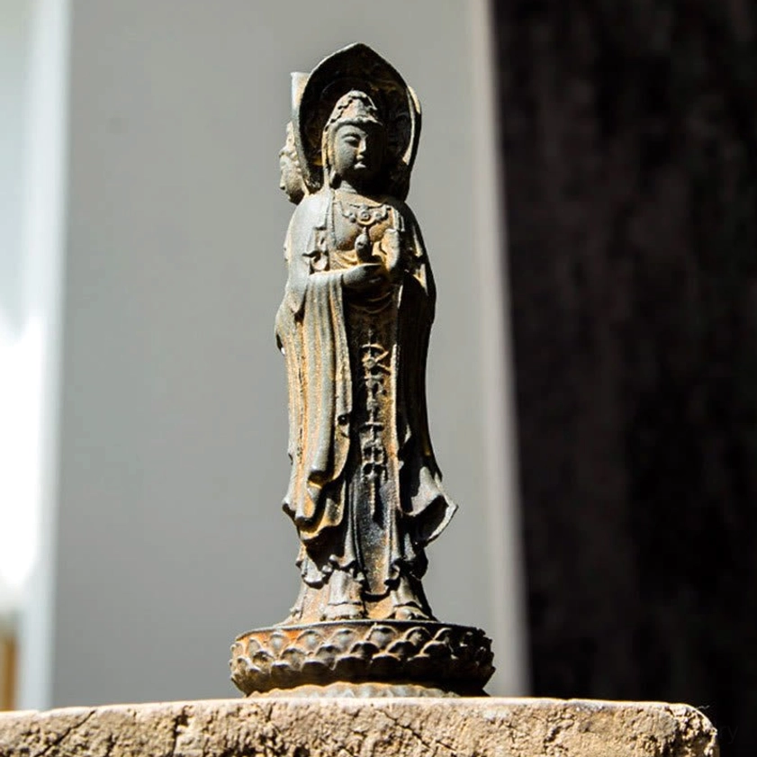 Three-sided Avalokitesvara resin statue on stone surface with weathered rusty texture and halo detail