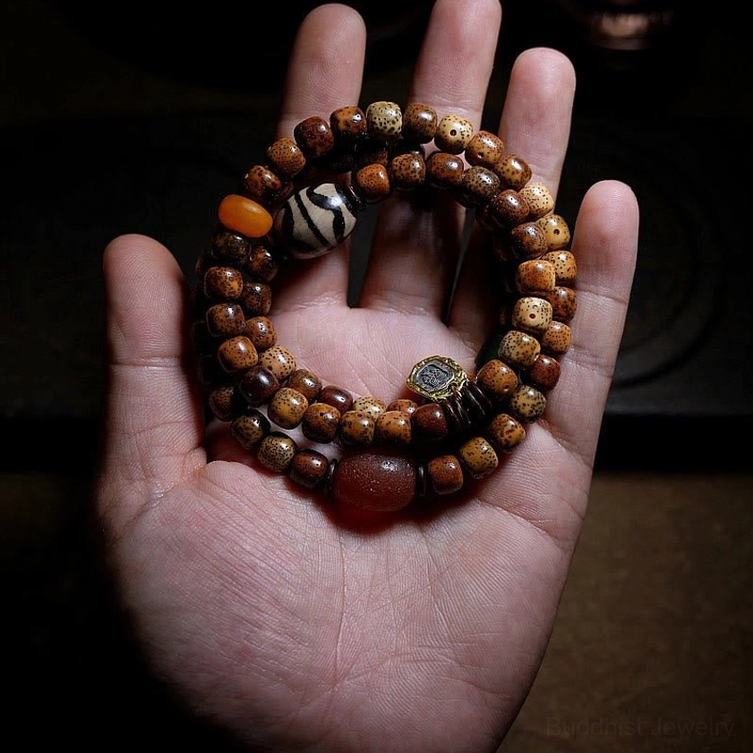 Triple wrap mala bracelet held in palm showing bodhi seeds and striped dzi beads handmade craftsmanship detail