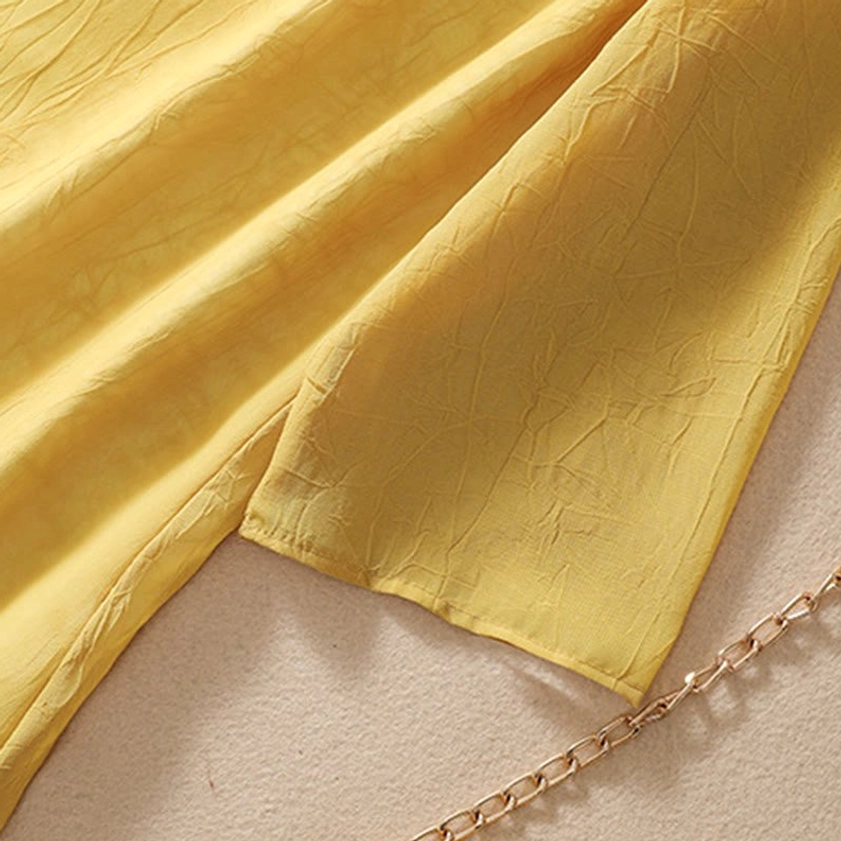 Side view of yellow tunic showing asymmetrical split hemline with soft fabric drape and flowing wide leg effect