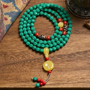 108-bead turquoise Buddhist prayer mala with dzi bead and pumpkin beads displayed on vintage textile, overhead view showing complete mala necklace