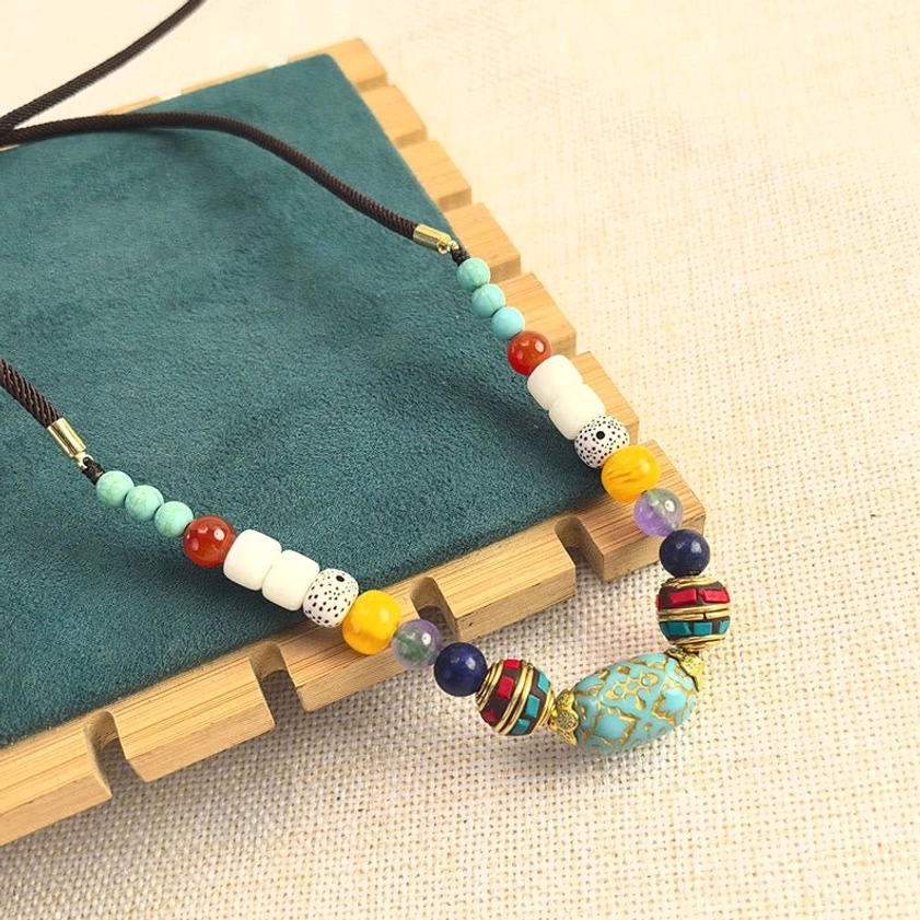 Natural turquoise chakra balance necklace with assorted beads on teal velvet fabric, spiritual jewelry styling