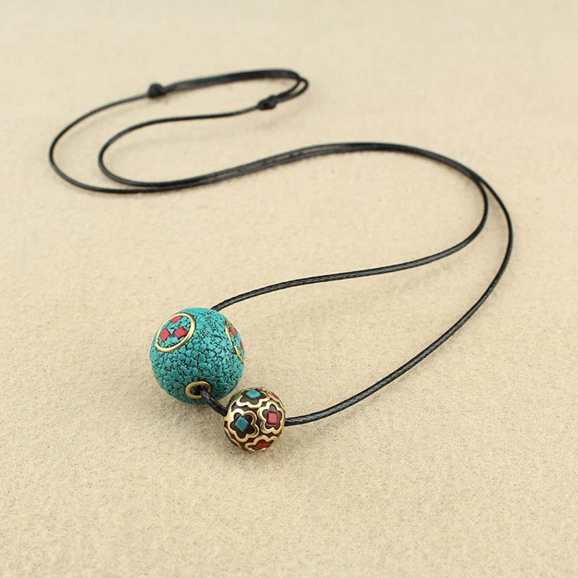 Flat lay of turquoise and enamel double bead Buddhist necklace with adjustable black wax cord on neutral background