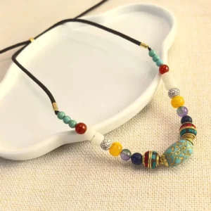 Handcrafted turquoise Buddhist beaded necklace with mixed gemstone beads and gold accents, displayed on white ceramic and linen