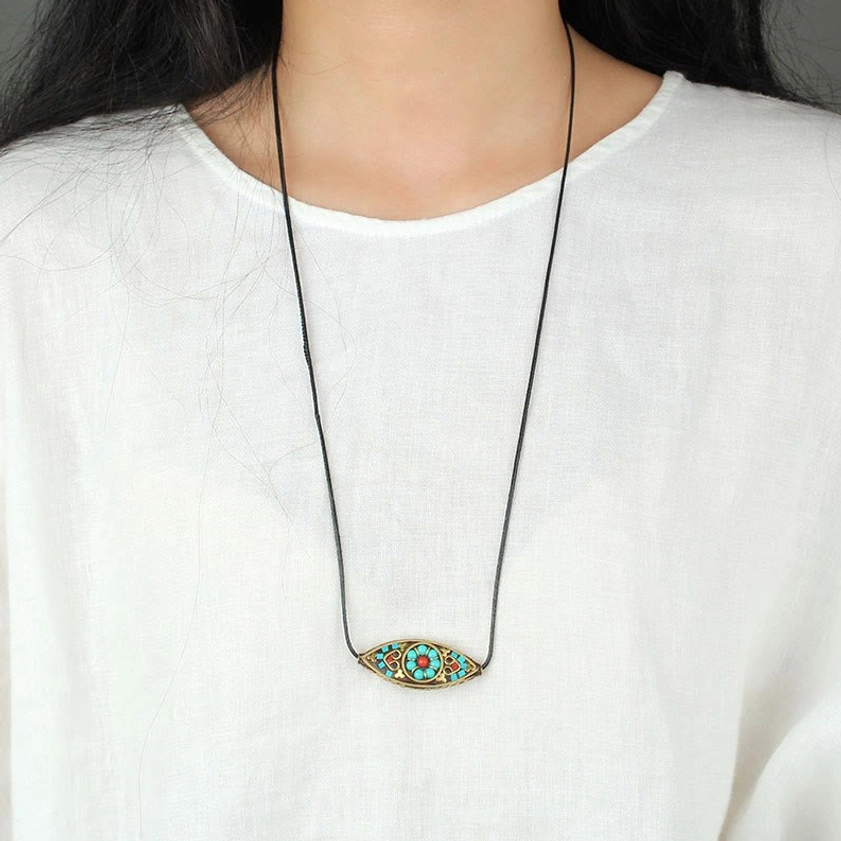 Turquoise Buddhist necklace pendant worn on female model at collarbone, short length styling