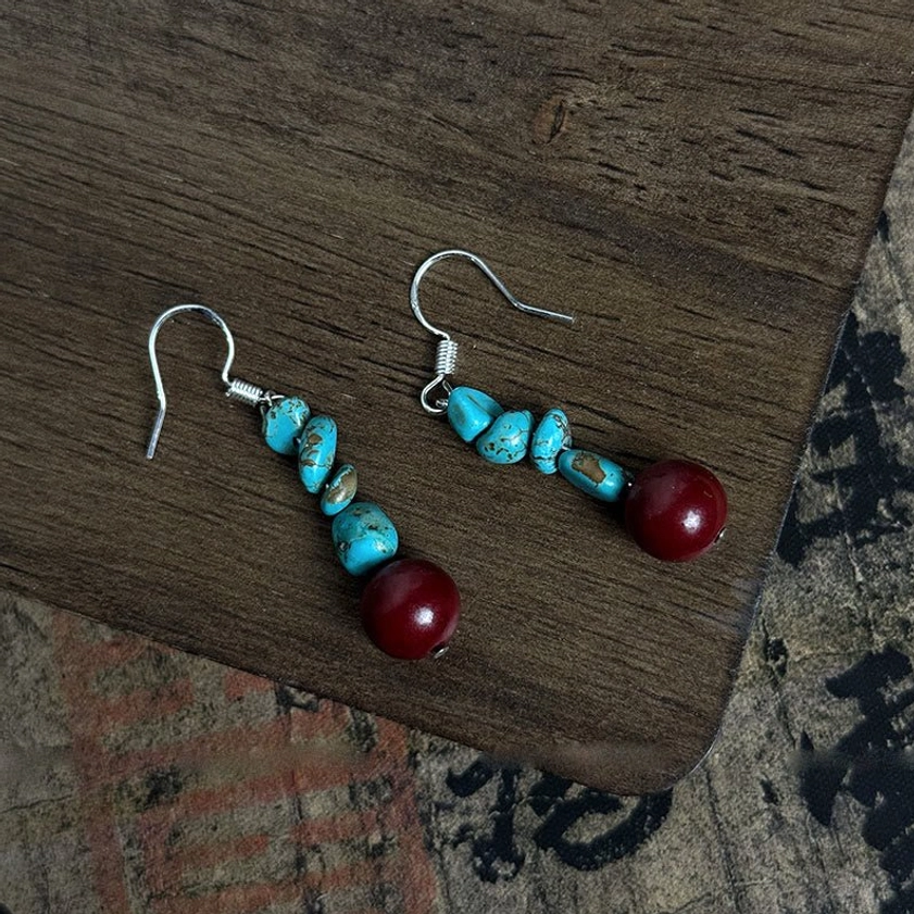 Overhead flat lay of paired turquoise cinnabar sterling silver Buddhist protection dangle earrings
