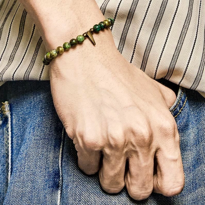 Side view of turquoise copper bracelet with tapered copper spike charm worn on wrist with denim